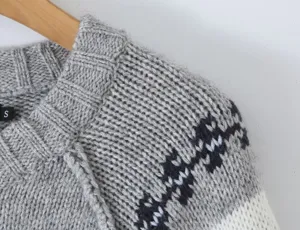 Close-up detail of grey women's knit sweater featuring vintage elk jacquard pattern on shoulder.