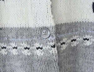 Detailed close-up view of a vintage knit cardigan featuring retro jacquard pattern and button.