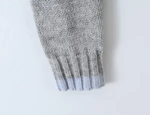Grey knit cardigan sleeve detail with light blue ribbed cuff, soft winter wear close up.