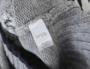 Detailed view of knit cardigan wash label showing premium fabric composition and brand info.