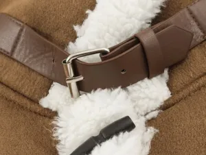 Close-up detail of brown shearling vest showing belt buckle and toggle button texture.