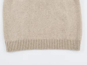Primer plano del dobladillo de punto fino acanalado en un chaleco beige sin mangas.
