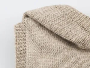 Detalle de tela de punto en color beige con textura acanalada suave para moda de invierno.