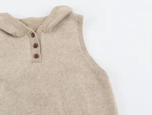 Primer plano detallado del chaleco de punto beige suave, destacando los finos botones.