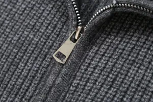 Close-up detail of dark grey knit cardigan zipper, premium textured fabric texture.