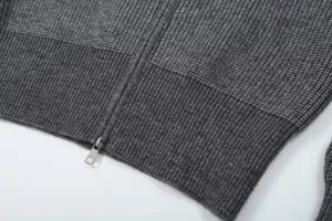 Close-up detail of grey knit cardigan hem, showing exquisite zipper and ribbed texture.