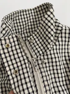 Close-up detail of the black and white gingham zip-up jacket collar and metal hardware.