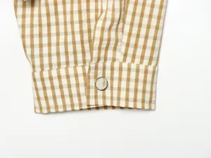 Close up of yellow and white plaid jacket sleeve cuff with metallic button detail.
