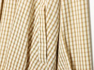 Close-up detail of stylish brown and white plaid women's short casual jacket pocket fabric.
