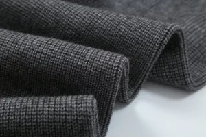 Detailed view of dark grey knitted fabric showing fine ribbed texture and soft quality.