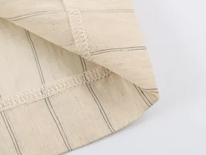 Close-up detail of women's fashion striped fabric garment hem with fine stitching texture.