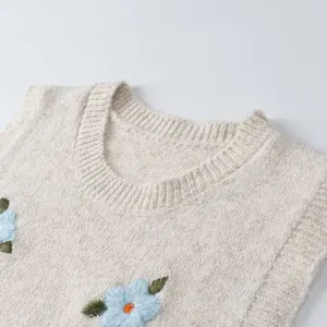 Chaleco de punto en color beige con elegante bordado floral azul en 3D y cuello redondo clásico.