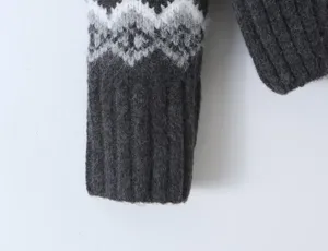 Detailed shot of a dark grey women's Fair Isle knit sweater sleeve with classic geometric patterns.