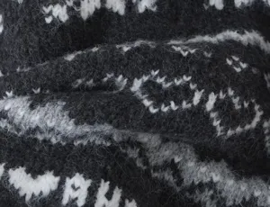 Detailed close-up shot of black and white knitted sweater fabric with jacquard pattern.