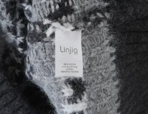 Detailed close-up shot of the black and white Fair Isle knit sweater fabric texture and brand label.