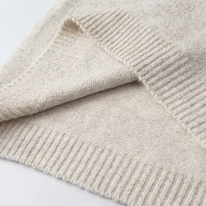 Vista detallada de chaleco de punto beige con dobladillo acanalado suave y textura premium.