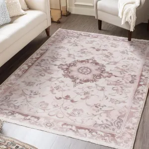 Detailed view of elegant pink floral area rug in a cozy living room scene with white sofa.