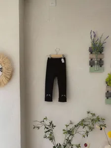 Vista dettagliata di leggings neri per bambine con grazioso ricamo di gatto sui polsini.