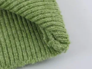 Green knit sweater detail close-up showing soft ribbed texture and fine craftsmanship.