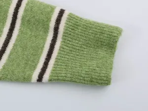 Close-up detail view of the green striped knit sweater sleeve with cozy ribbed cuff texture.