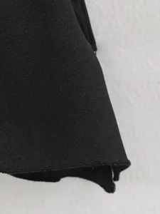 Black irregular ruffle skirt detail view showcasing the draping fabric texture and fine hem stitching.