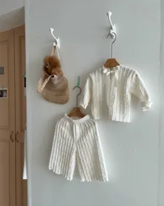 Detail shot of toddler white jacquard long sleeve top and wide leg pants set with bow.