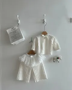 Detail shot of white baby girl jacquard long sleeve top and ruffle wide leg pants set.