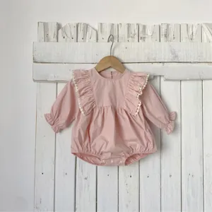 Baby pink long-sleeve romper detail, featuring large ruffle shoulders and delicate lace trim.