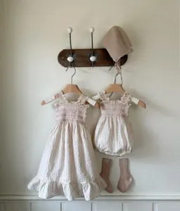 Detailed shot of baby girl smocked strap dress, romper, bonnet and socks set, hanging display.