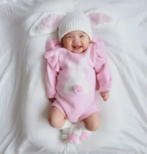 Close-up detail of the infant wearing a cute pink knit bunny romper with pom-pom.