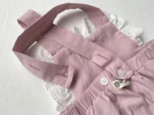 Infant baby girl pink cotton romper detail, white lace trim and cute button closure.