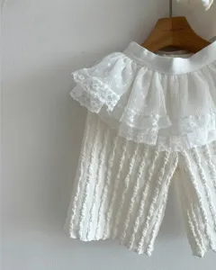 Detail shot of white infant girl wide-leg pants featuring delicate layered lace ruffles.