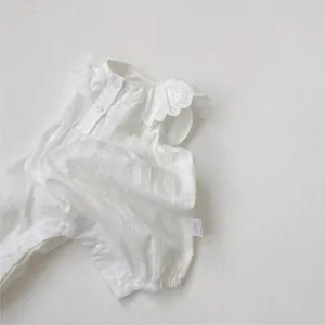 Close up view of infant baby white cotton romper, sweet lace collar and soft dotted texture.