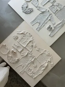 Gedetailleerd overzicht plat van babykleding sets van gespikkeld katoen, mutsjes en accessoires.