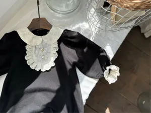 Chic baby girl lace collar romper, elegant black infant bodysuit with pearl buttons.