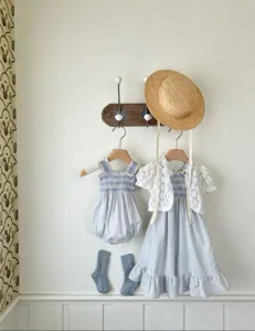 Detailed view of baby girl summer blue check romper and lace cardigan outfit setup.