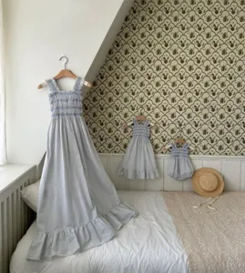Charming blue white checkered baby toddler smocked dresses and romper displayed in room.