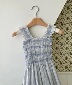 Detailed close-up of blue and white checkered baby smocked romper featuring cute ruffles and straps.