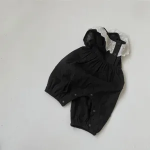 Baby black cotton romper detail featuring delicate white lace collar and convenient snap buttons.