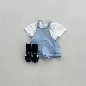 Detailed view of infant denim overalls and white t-shirt outfit with casual sneakers.