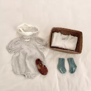 Babykleidung Detailset, gestreifter Strampler, Spitzenstirnband, Weidenkorb und süße Socken.