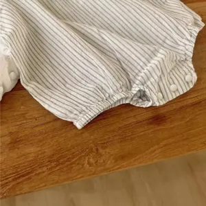 Detailansicht des Baby-Stramplers mit Streifen, weicher atmungsaktiver Stoff mit elastischen Knöpfen.