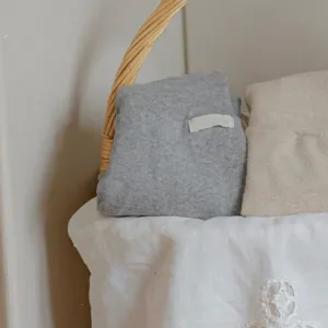 Dettaglio abbigliamento in maglia per neonati, tessuto morbido accogliente, stile minimalista.