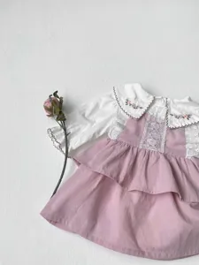 Gedetailleerd overzicht van het baby meisjes herfst overhemd en roze gelaagde jurkje.