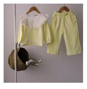 Détail ensemble sweat jaune enfant, col à volants en dentelle et pantalon assorti.