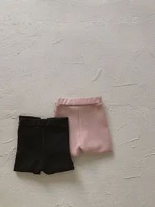 Dettagli dei graziosi pantaloncini casual per bambini in nero e rosa, tessuto morbido.
