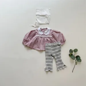 Baby clothing set detail showing cute mauve blouse, striped leggings and white lace bonnet.
