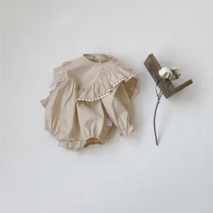 Detail view of a beige baby girl long sleeve romper featuring a large ruffled lace collar.