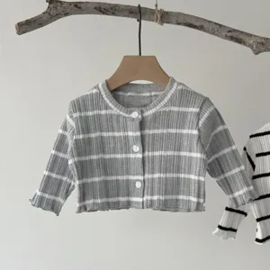 Detail view of baby ribbed striped cardigan, soft knit fabric, cozy neutral aesthetic hanging.
