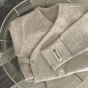 Gedetailleerd overzicht van baby katoenen omslagvest met kleurrijke stippen en ribbels.